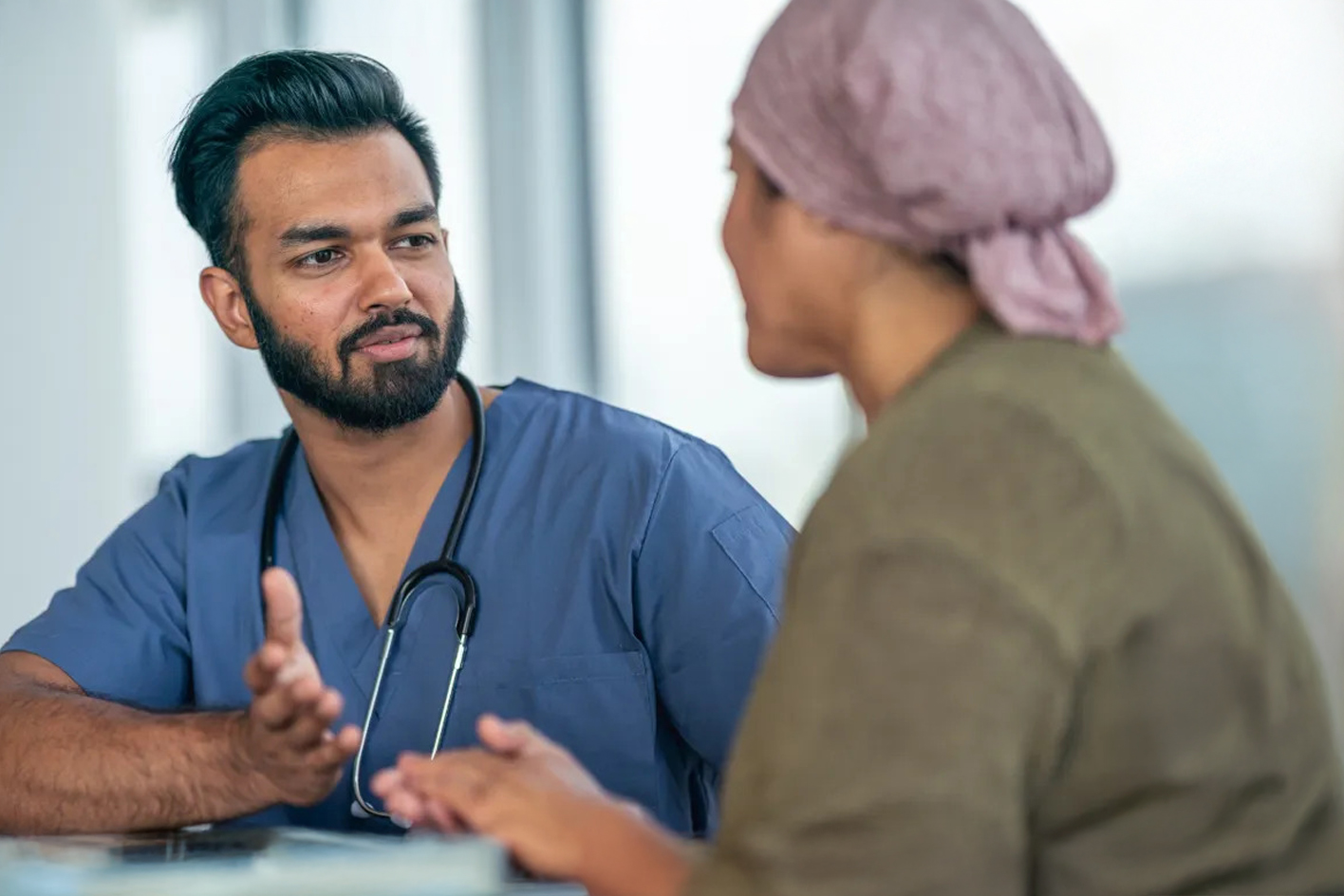A clinician in consultation with a female patient wearing a headscarf