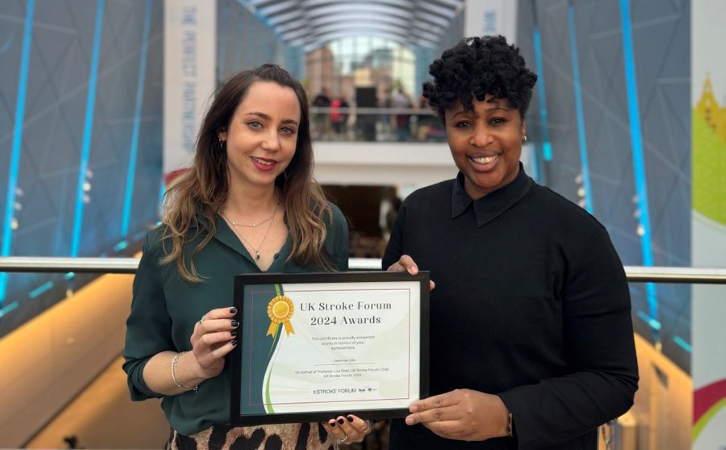 
Two ladies holding a certificate and smiling