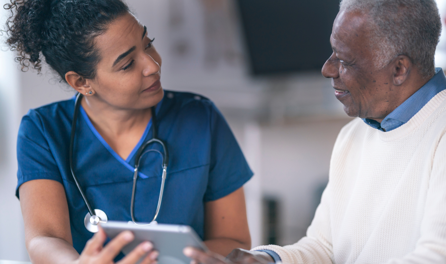 A doctor showing an older patient information on a digital tablet