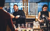 Male and female bar staff serving customers