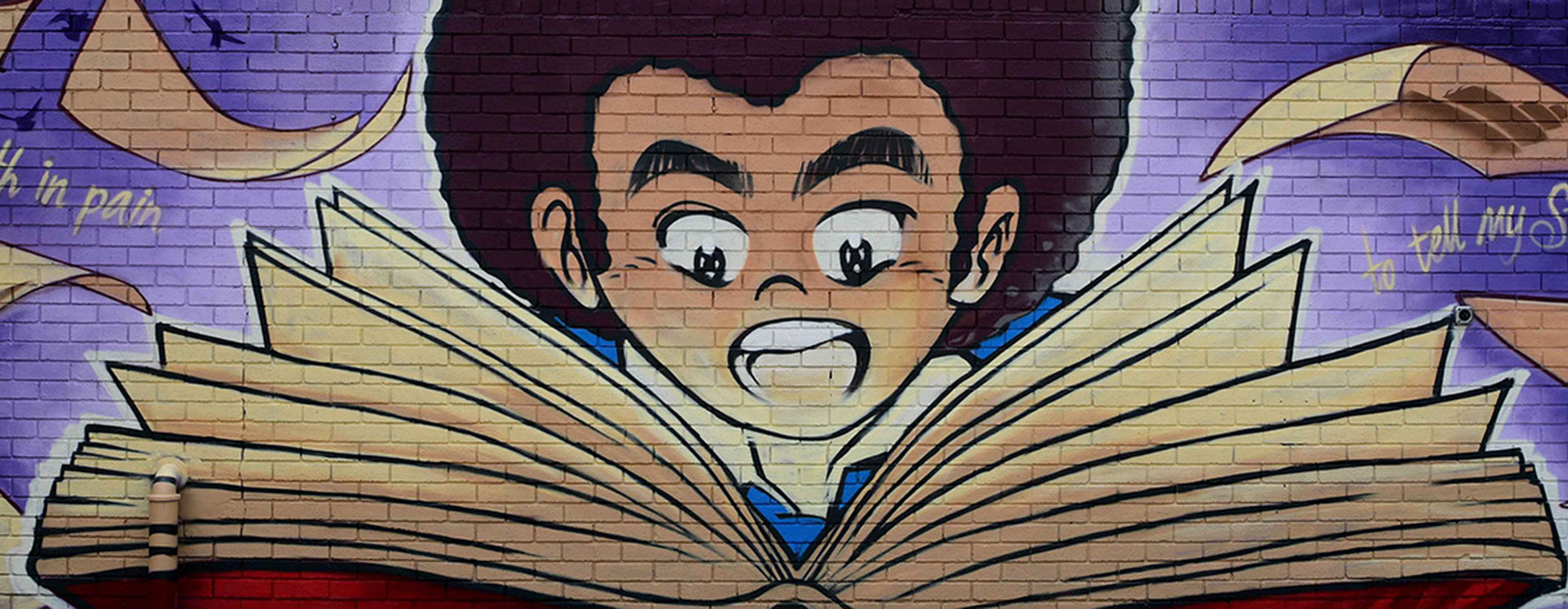 Mural painted on a wall showing a person reading a book