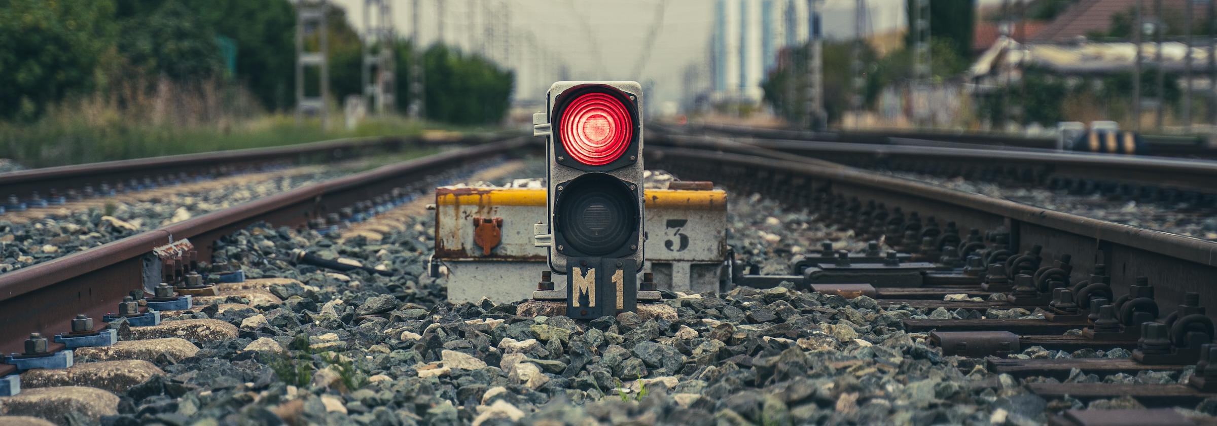 A red light sitting between two sets of railway tracks