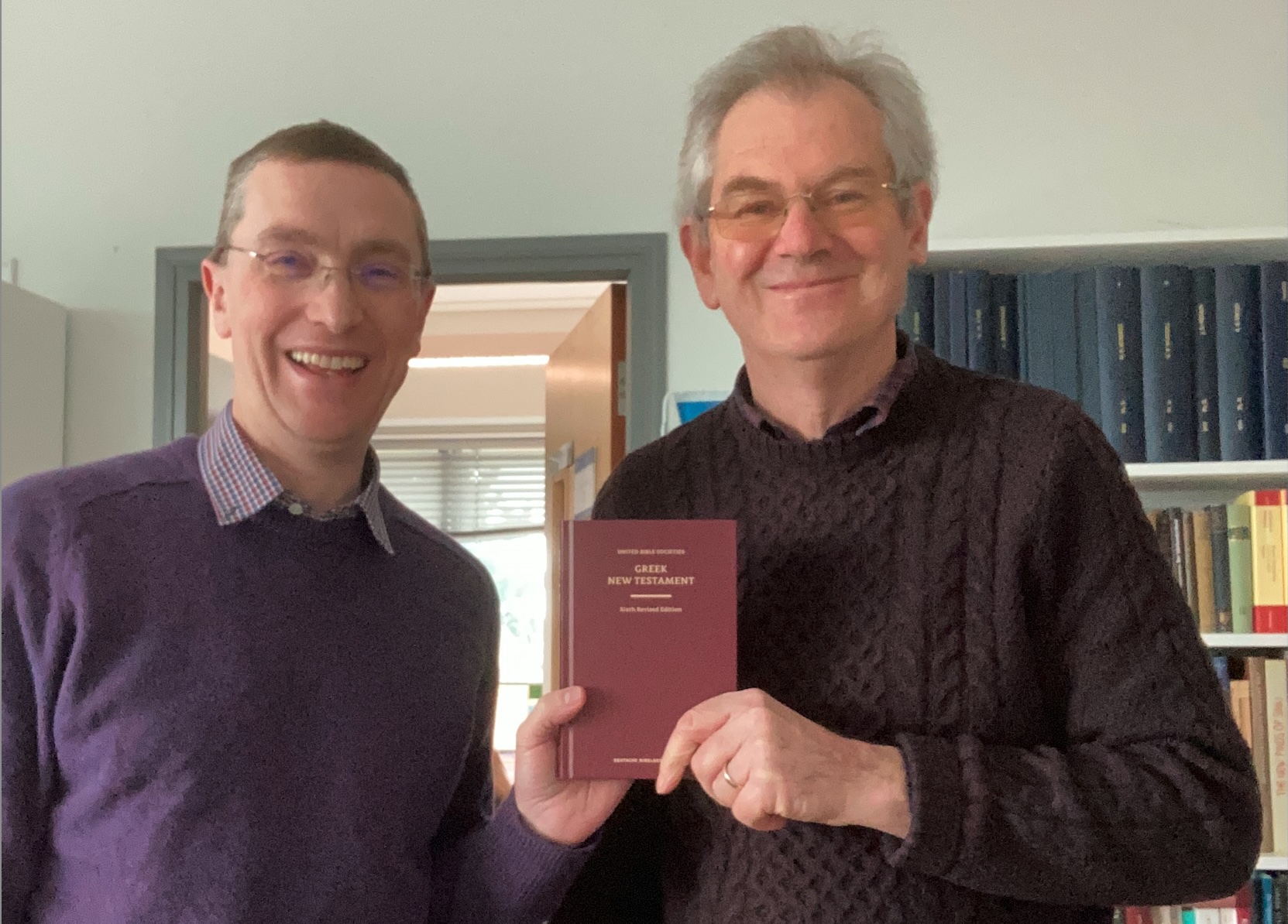 Two men holding a small red book