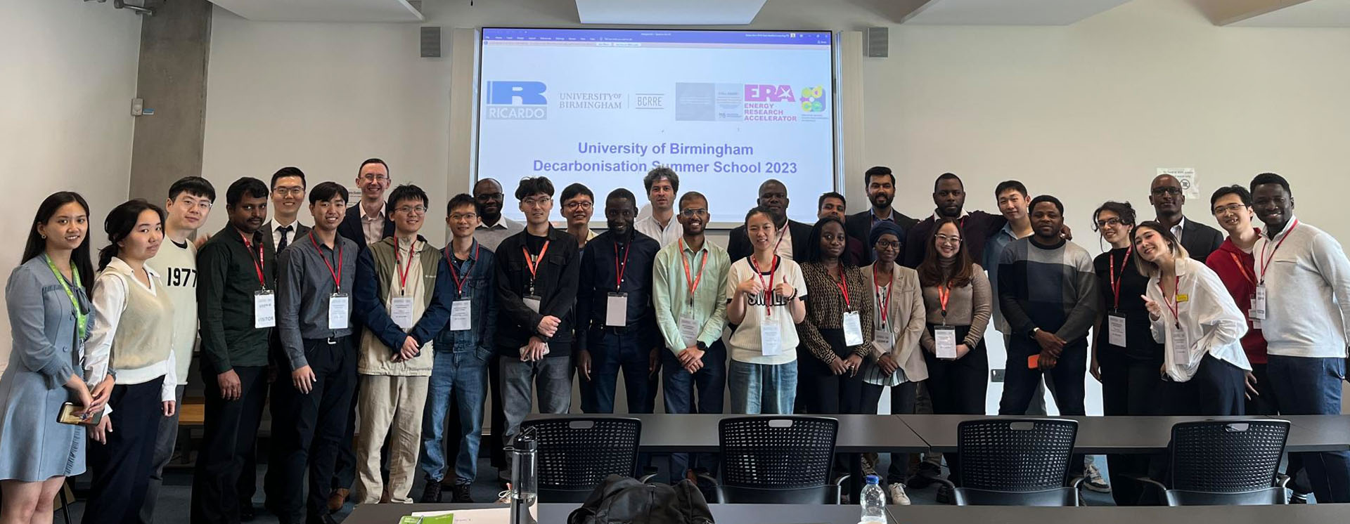 A group of postgraduate researchers from 11 UK universities standing in front of a presentation screen