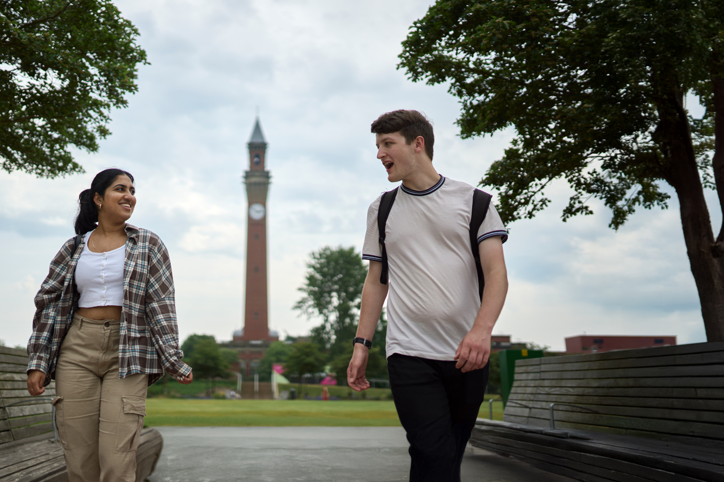 Two students walking and talking, with Old Joe clocktower visible behind them