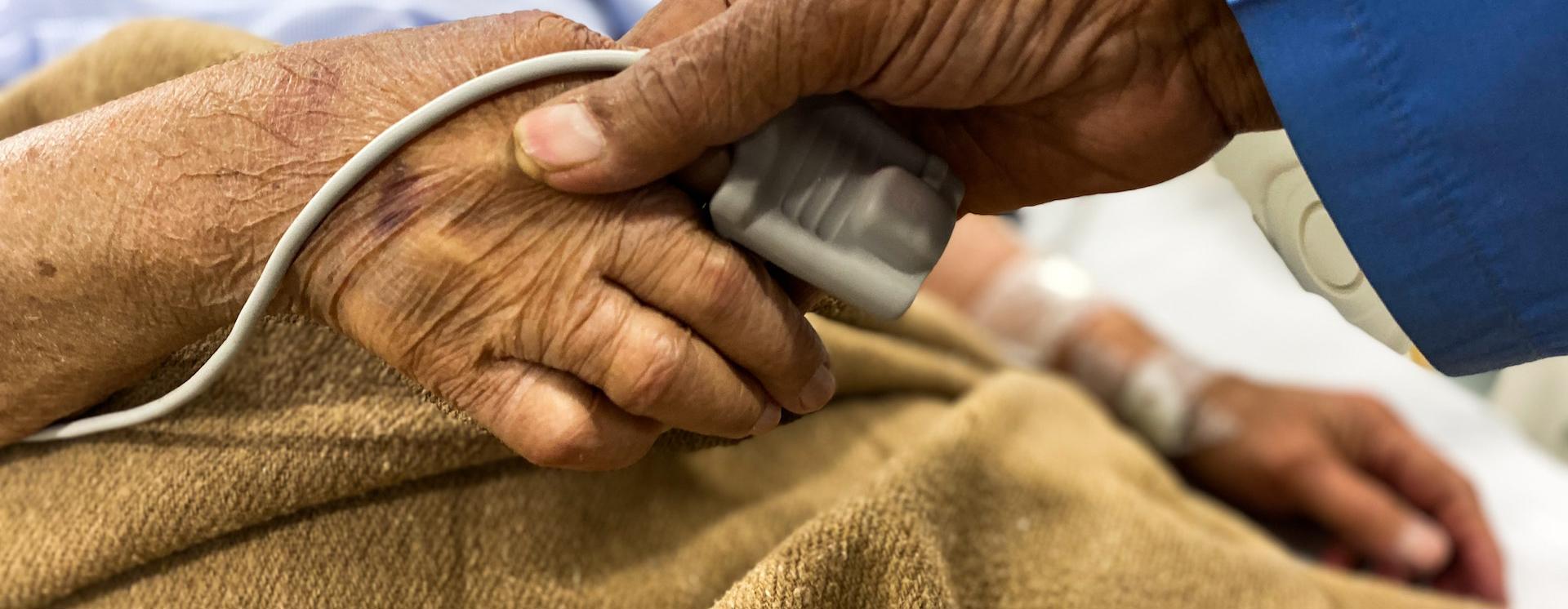 Doctor taking oxygen and pulse readings from an elderly patient