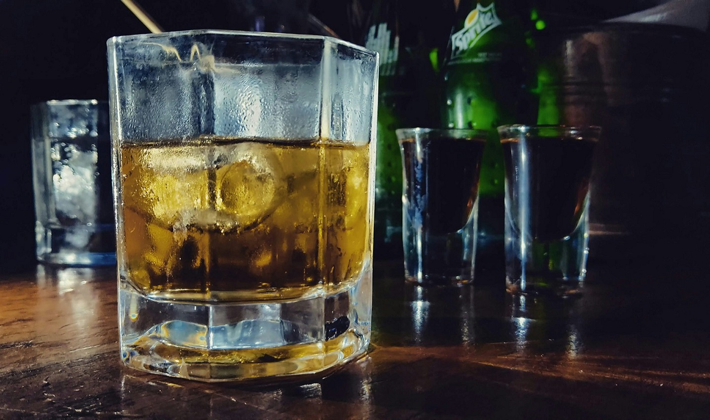 Several glasses on a table, one mostly filled with an alcoholic drink