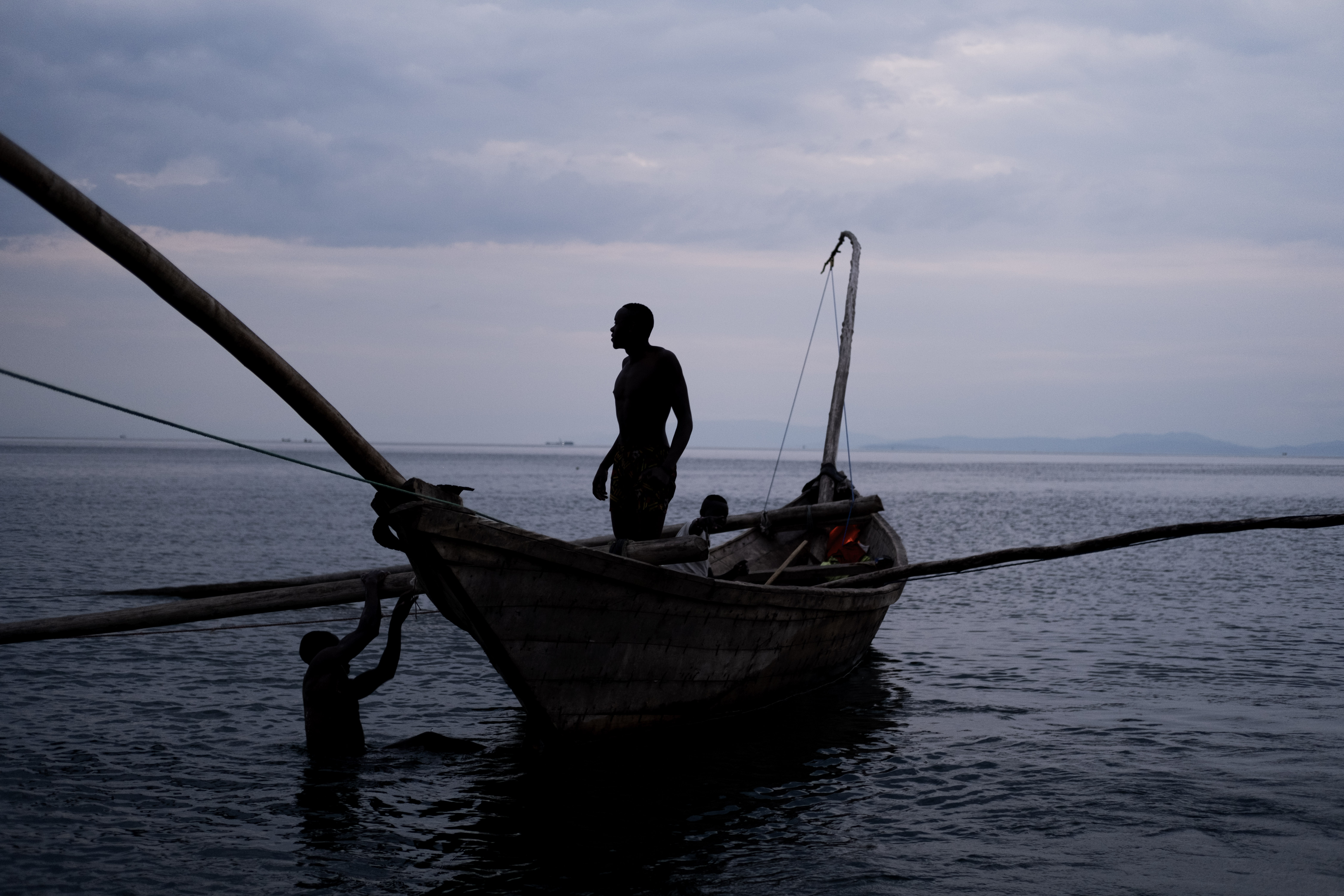 Rwandan fisherman in boat with colleague in the water