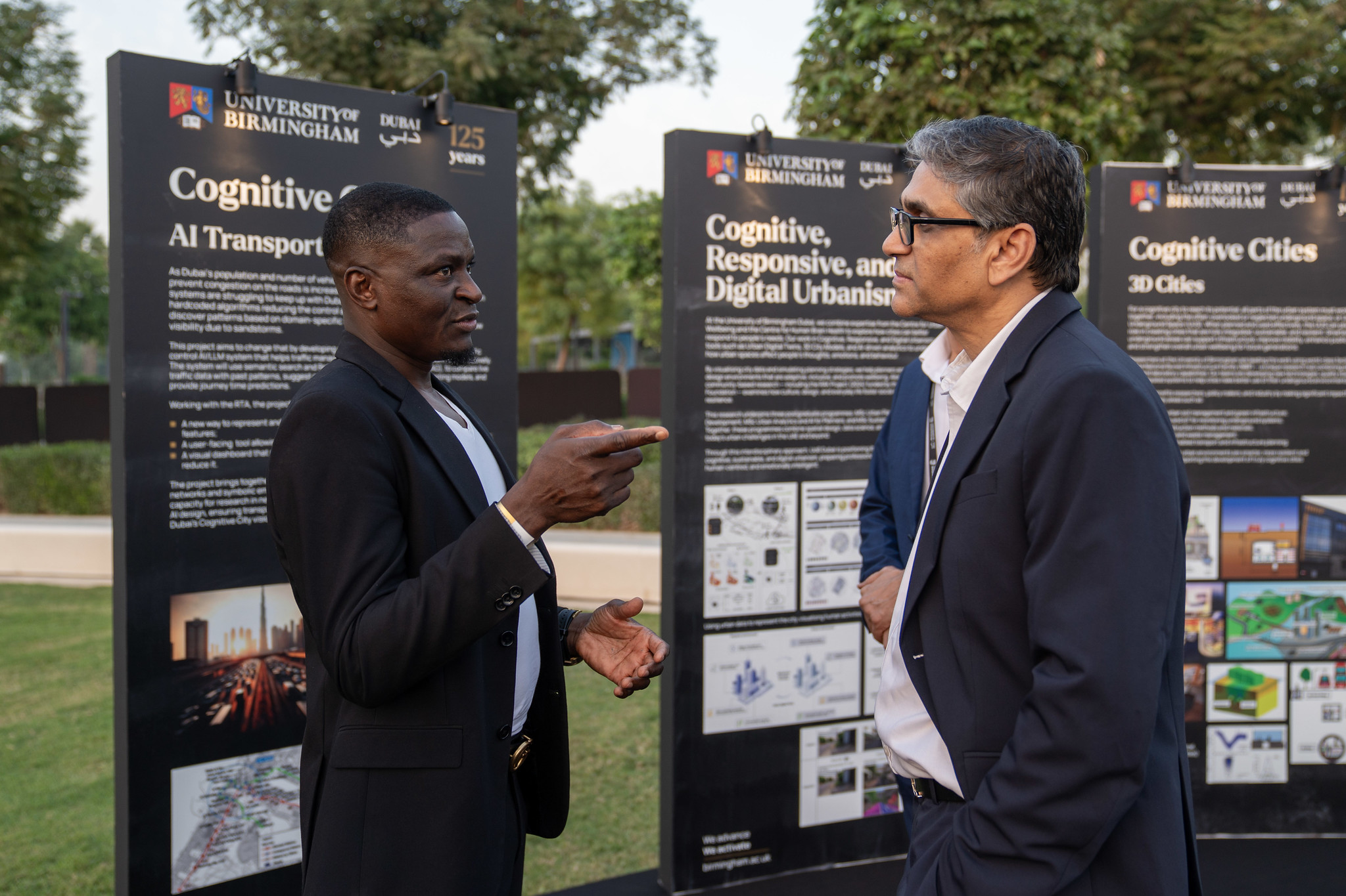 Guests discussing research display boards at the University of Birmingham Dubai 125th anniversary event.