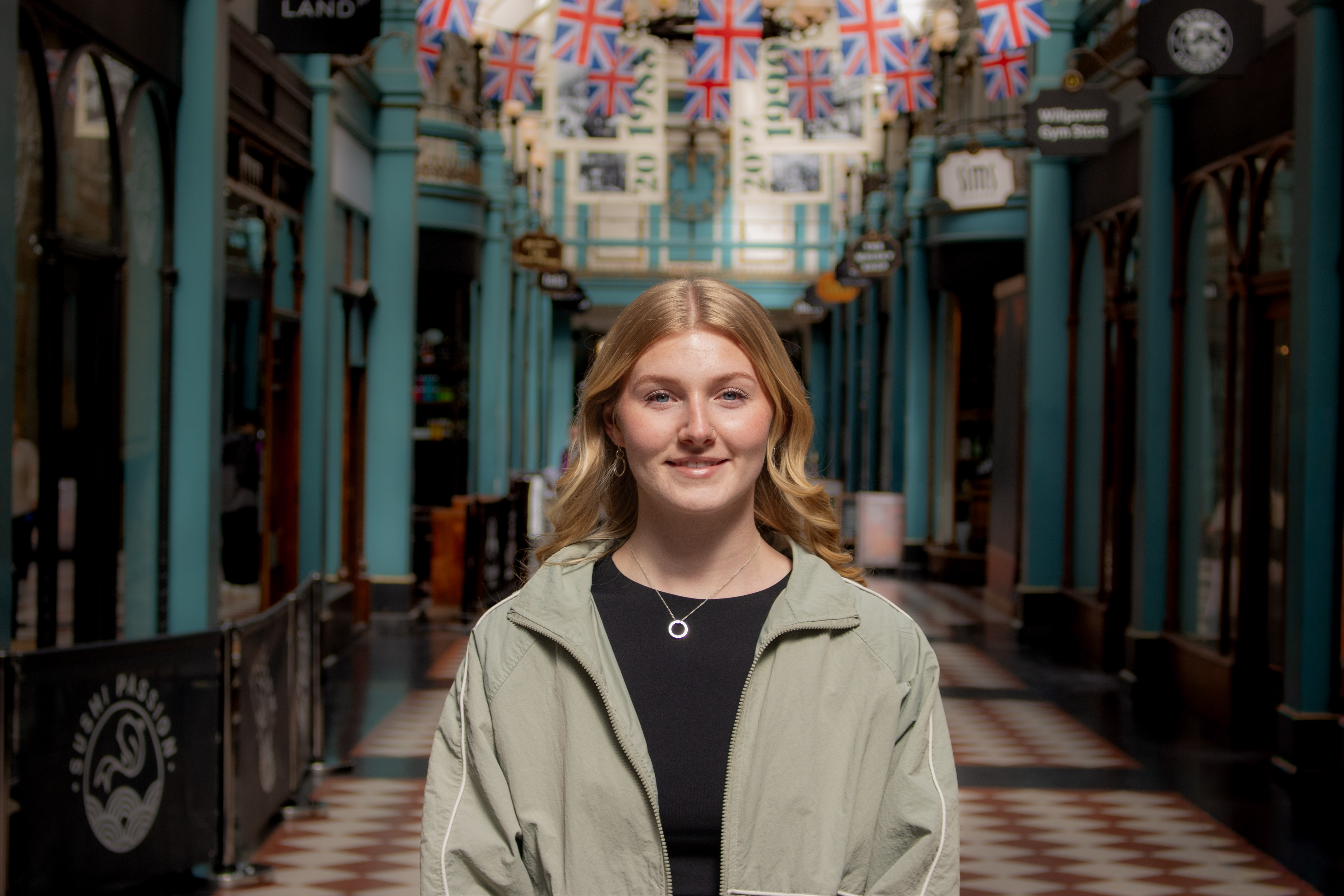 A young girl stood in an arcade full of lots of shops