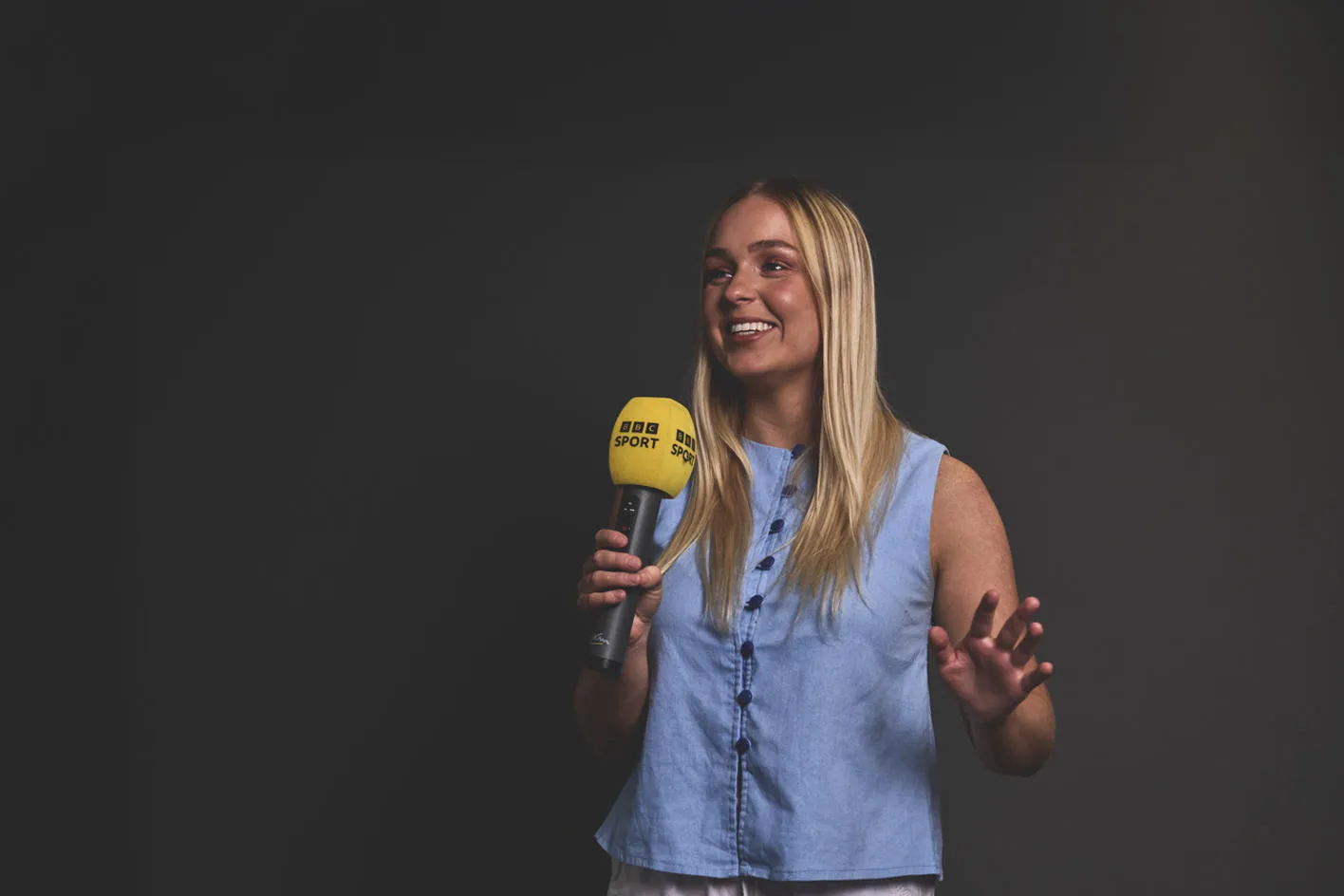 Elizabeth holding a microphone with a BBC Sport-branded foam windshield
