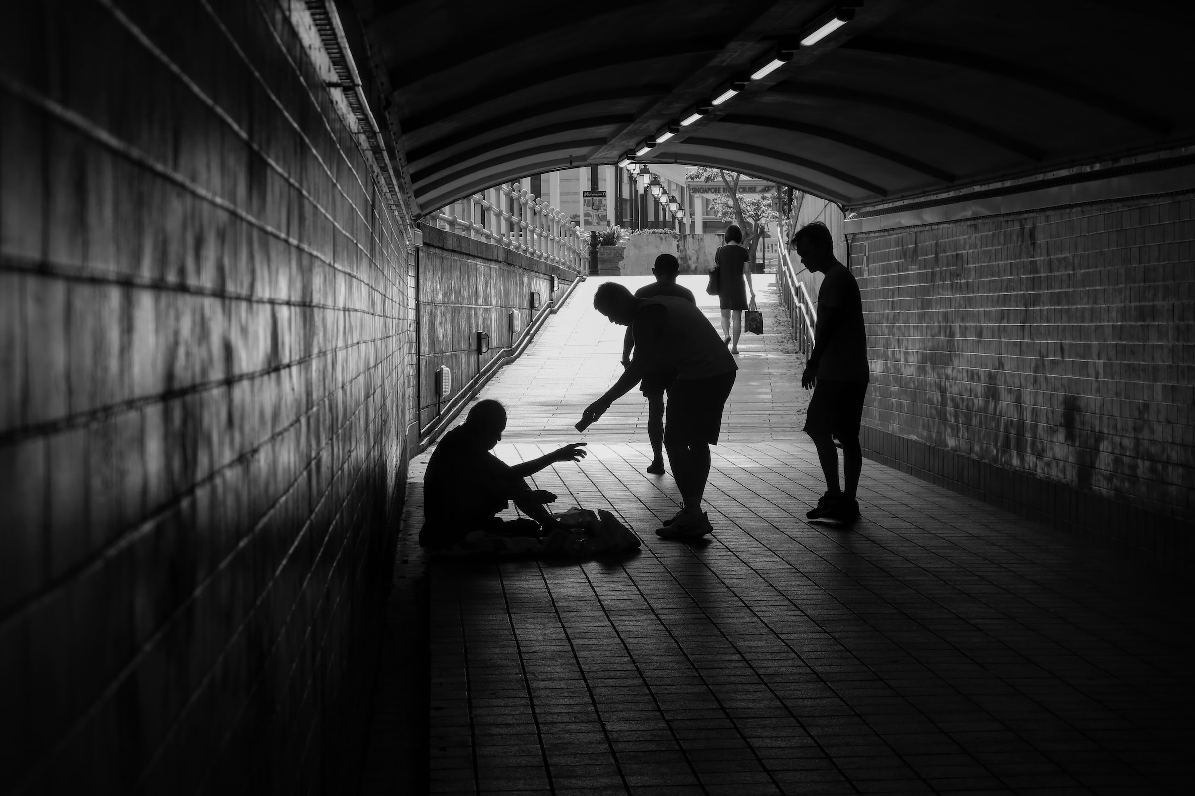 Beggar in underpass receiving money from passers-by