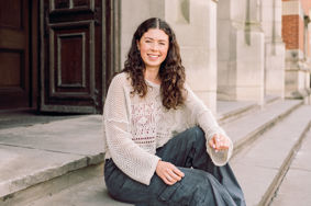Emily sitting on the steps of the University of Birmingham's redbrick Aston Webb building
