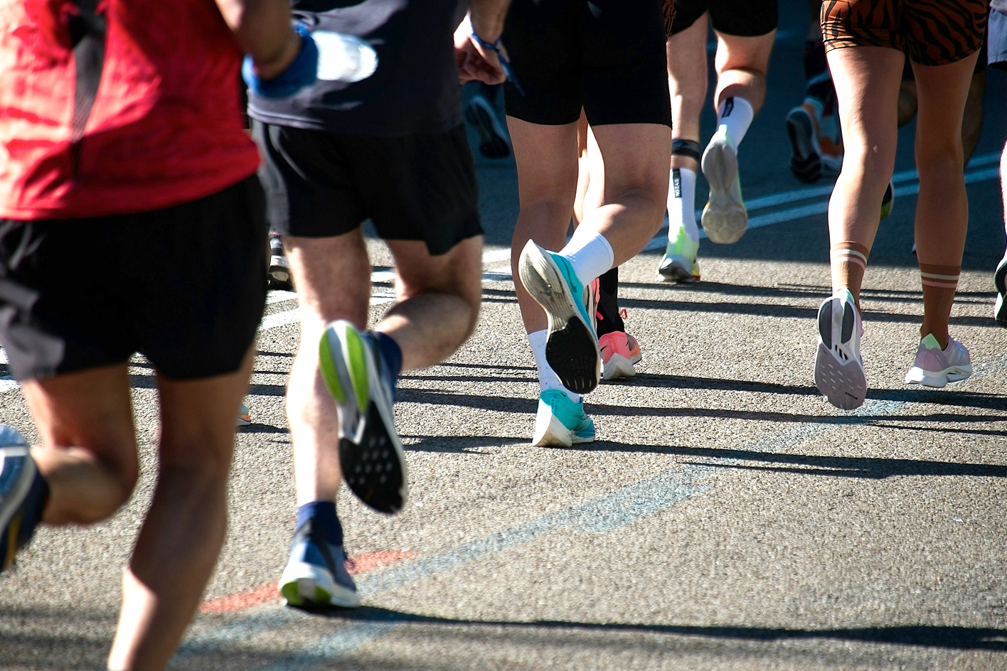 The legs of runners in a road race