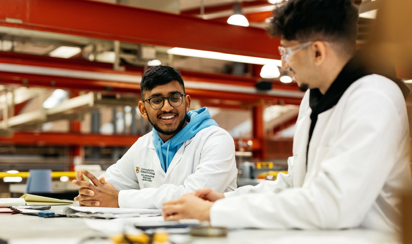 Two people in lab coats sitting at a table
