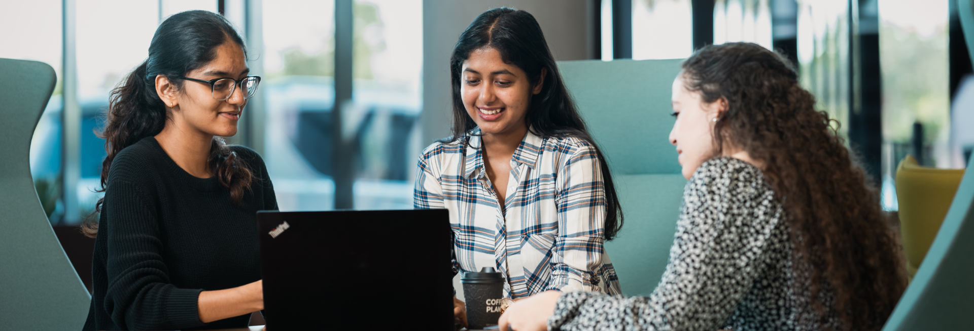 A group of female students sitting together, looking at the laptop screen