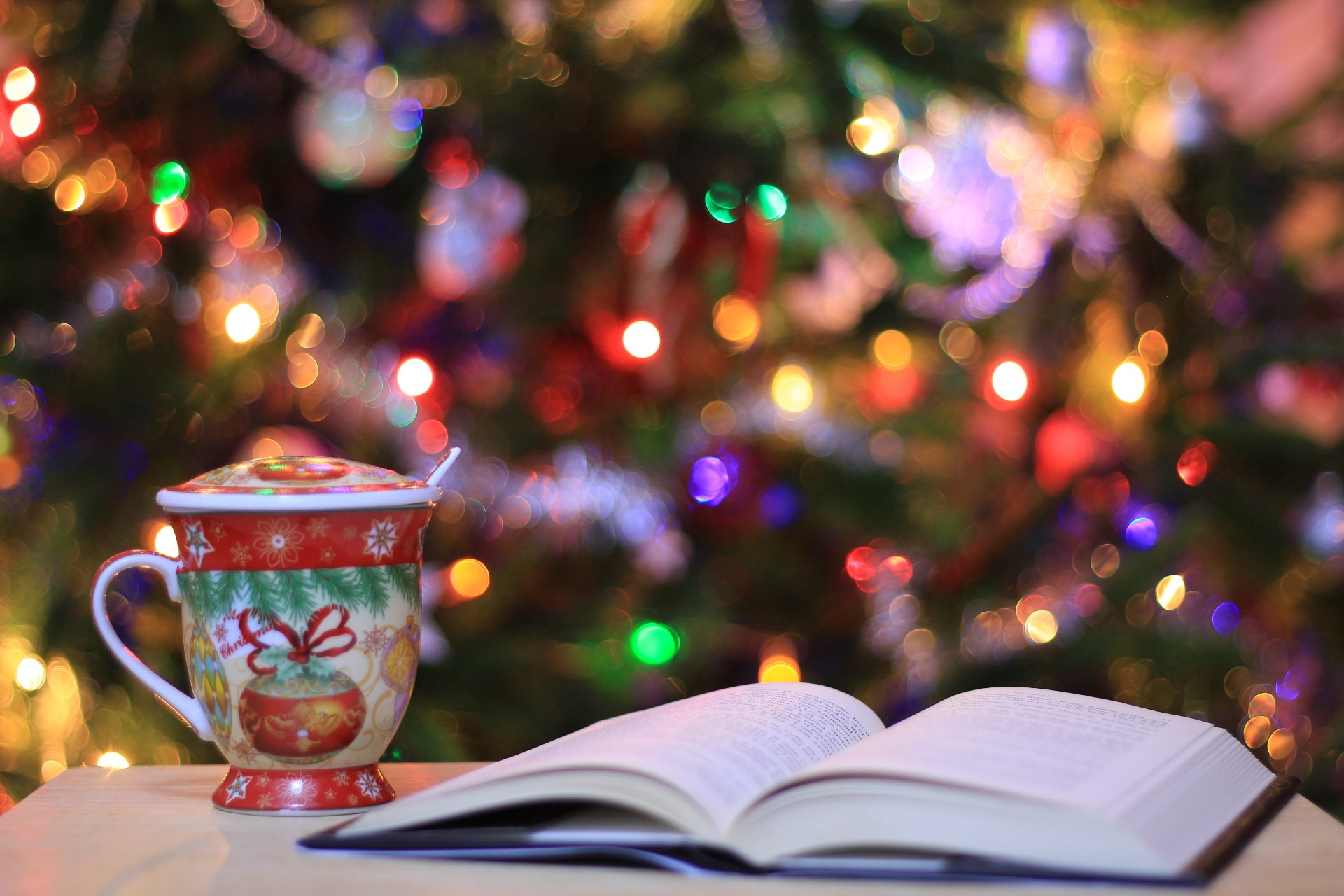 book and a cup with a christmas tree in the background