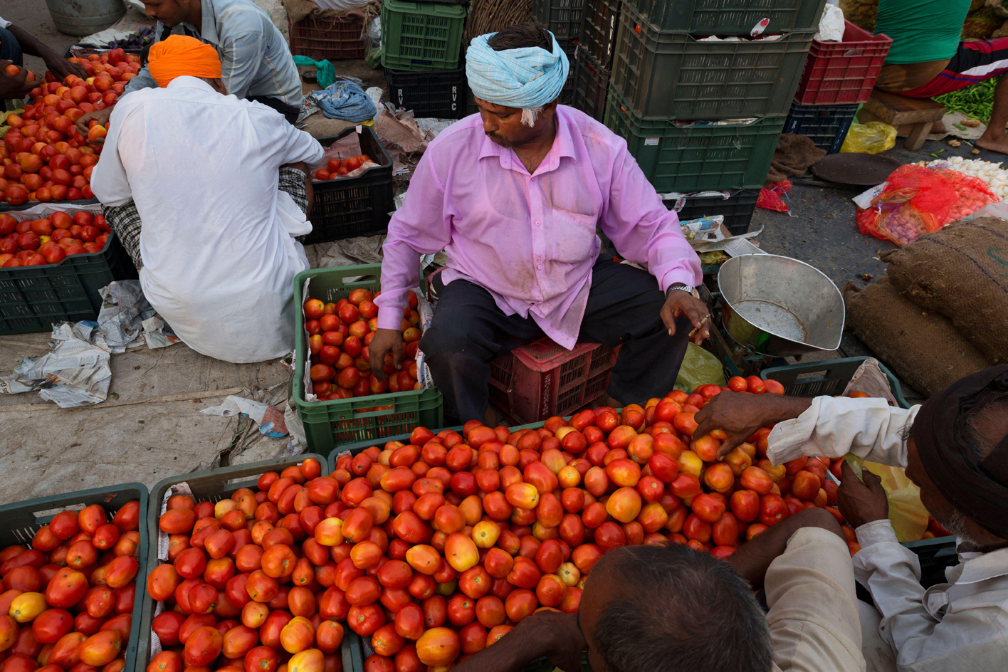 Indian street sellers sitting with crates of fruit and vegetables
