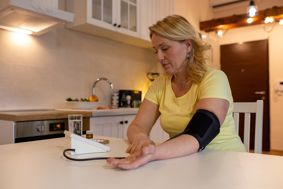 A woman testing herself using blood pressure machine