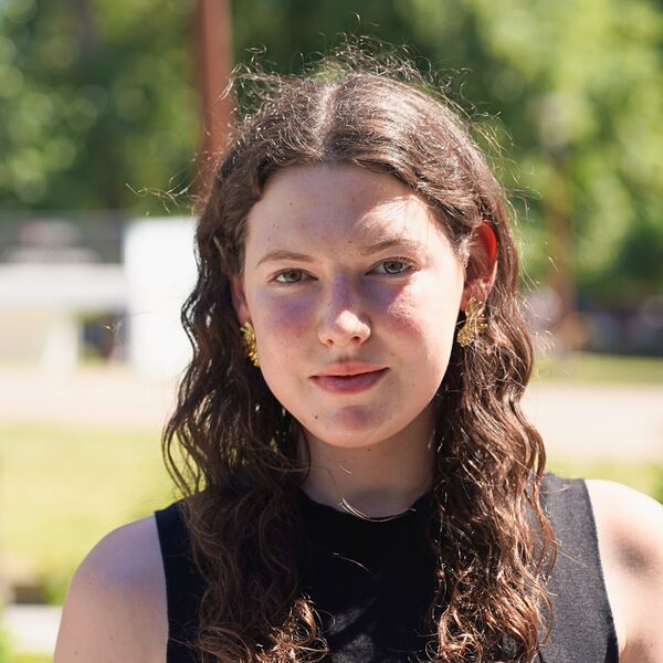 Glafki wearing a black top smiling towards the camera on a campus backdrop