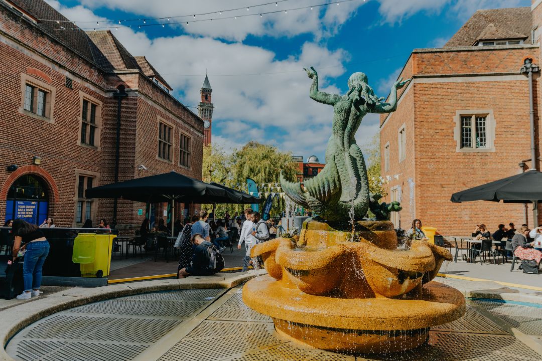 Guild Mermaid statue with Old Joe in the background and students milling around.