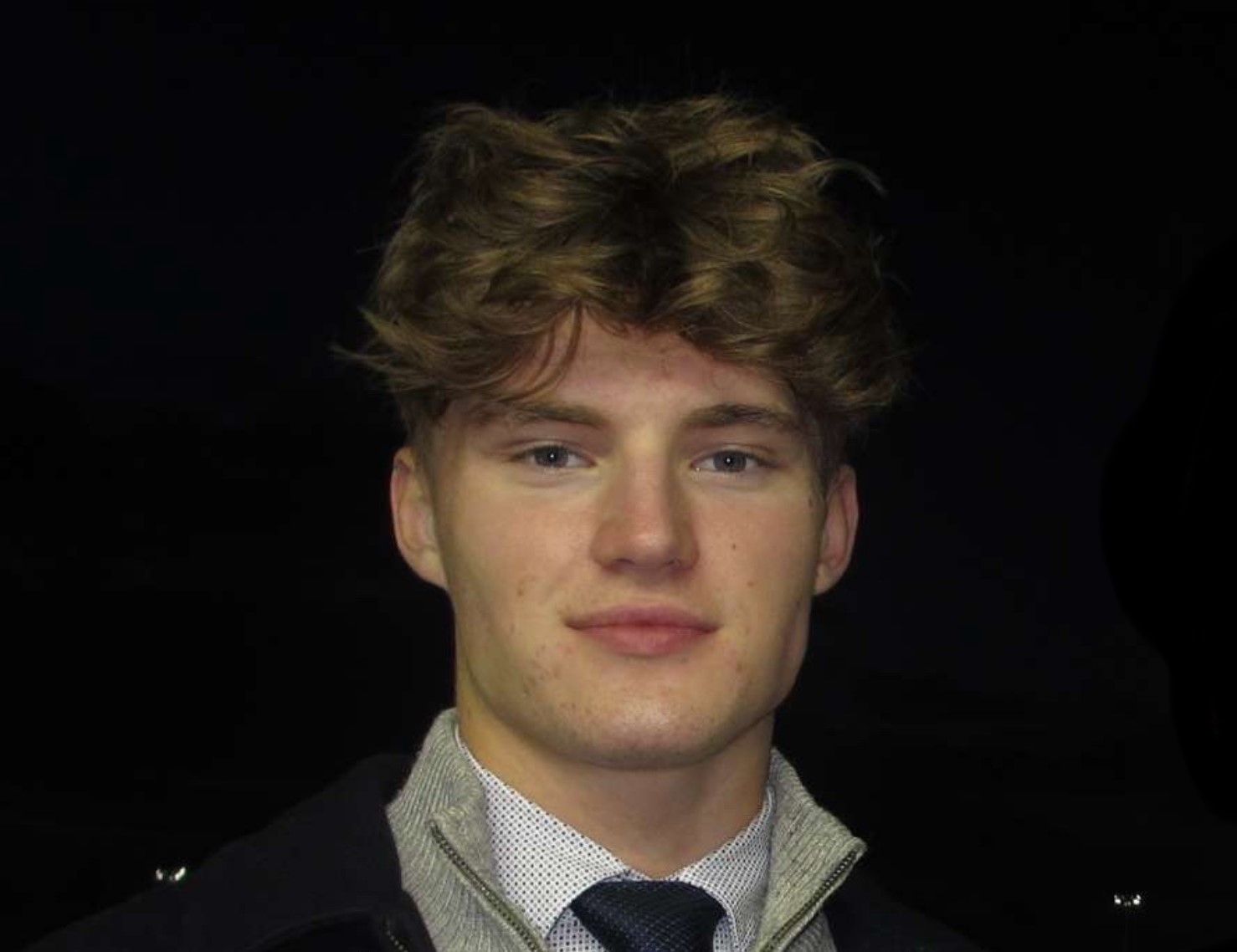 Guy smiling at the camera against a dark background