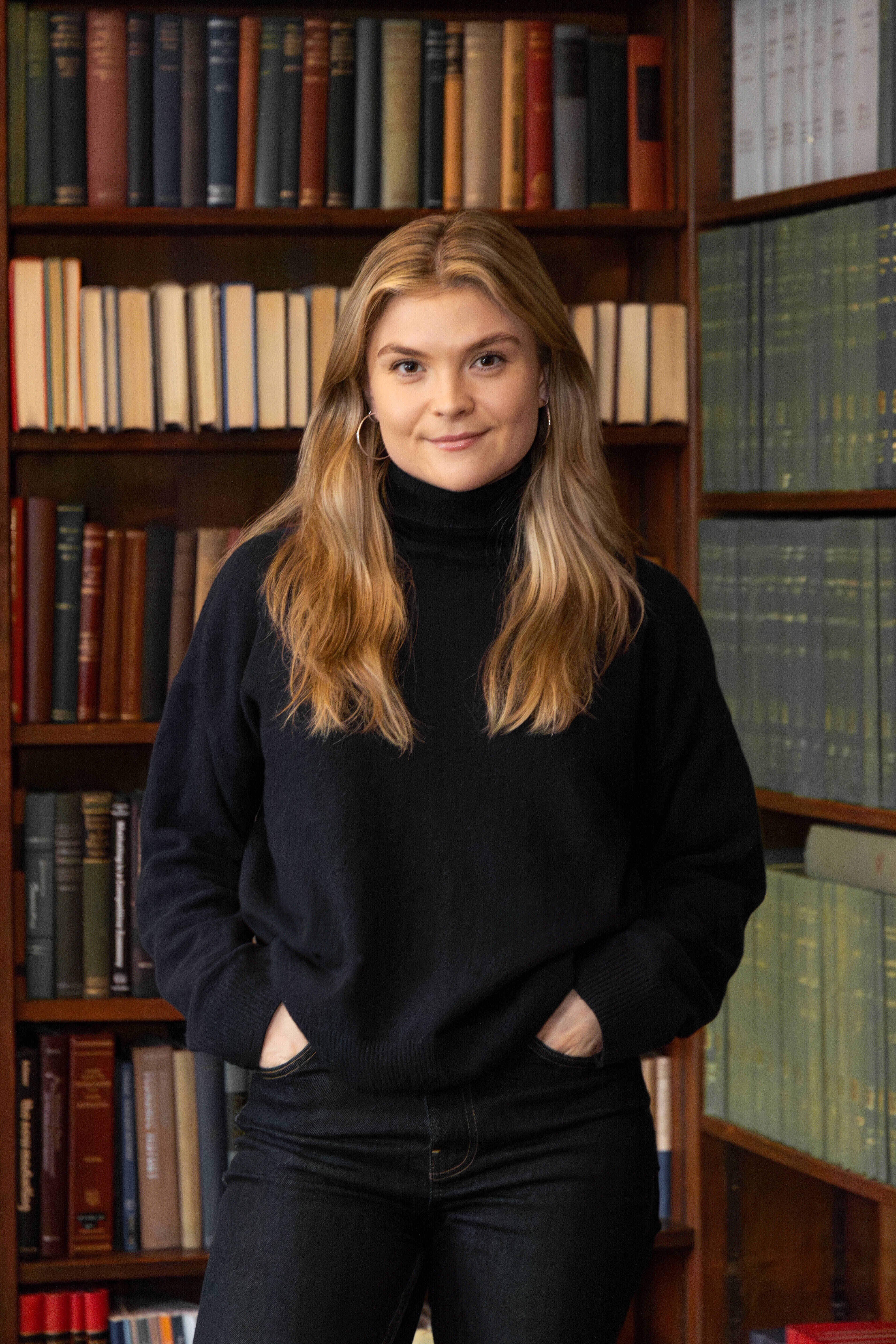 Harriet standing in front of a library smiling with her hands in her pockets