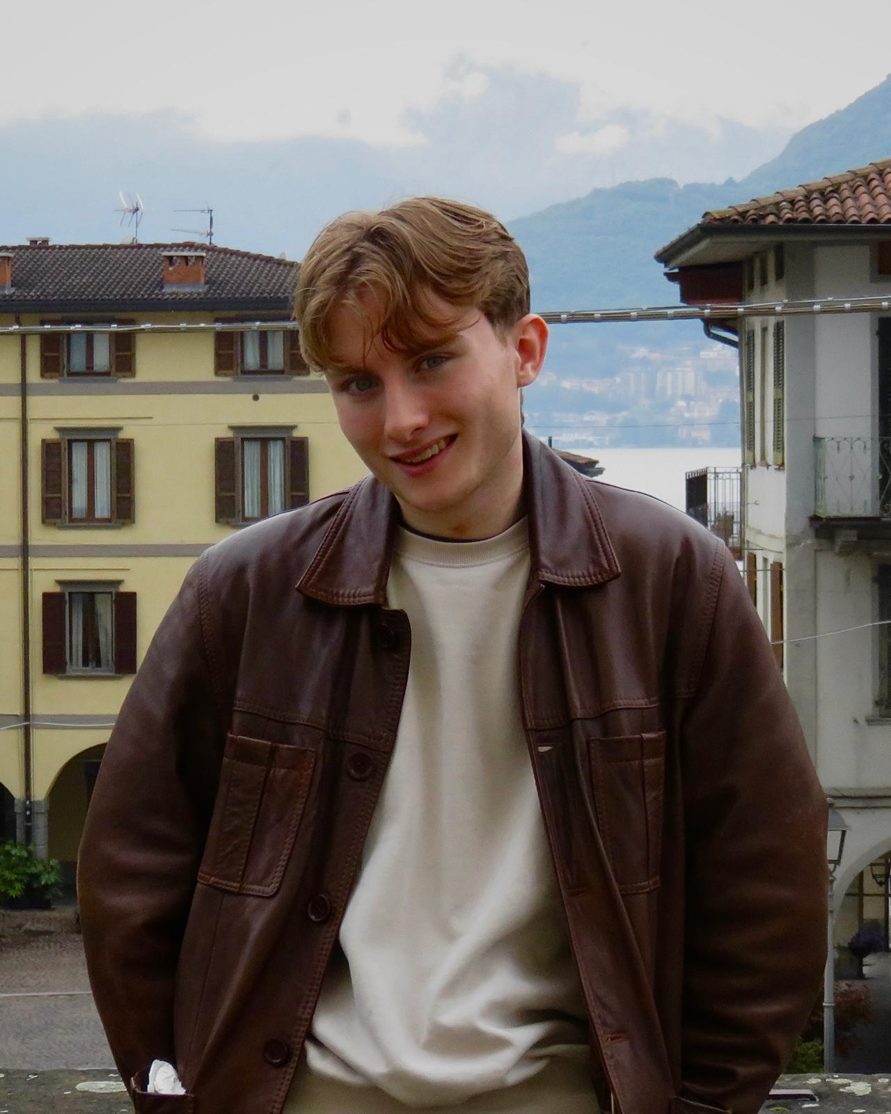 Harry James wearing a brown jacket with a white top underneath