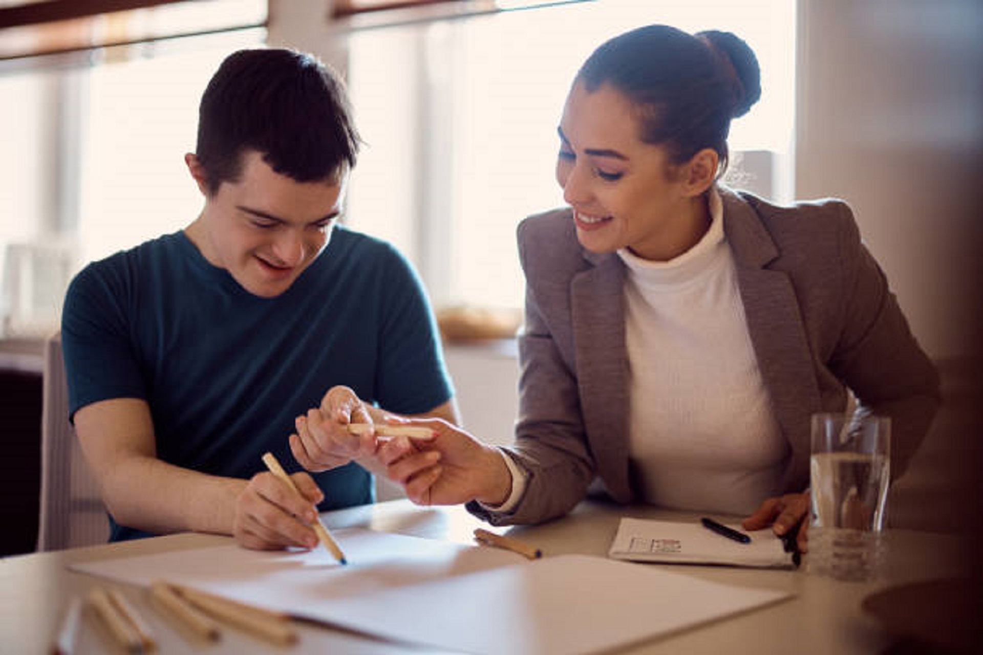 Woman helping young man to read.  