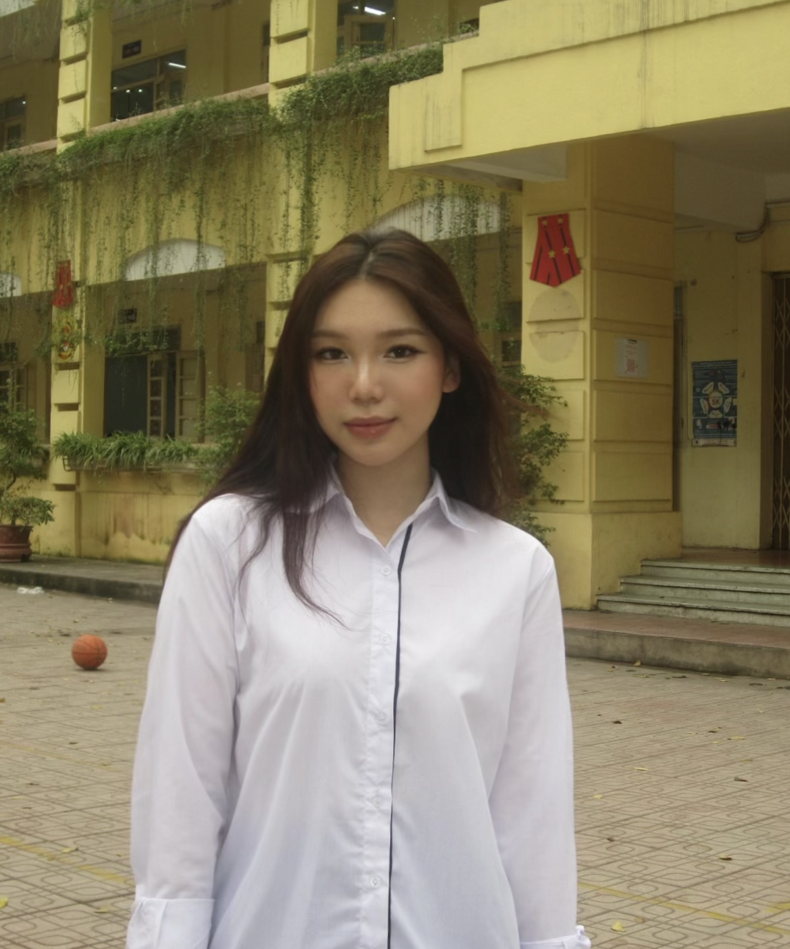 Hien is stood smiling at the camera with a yellow building in the background