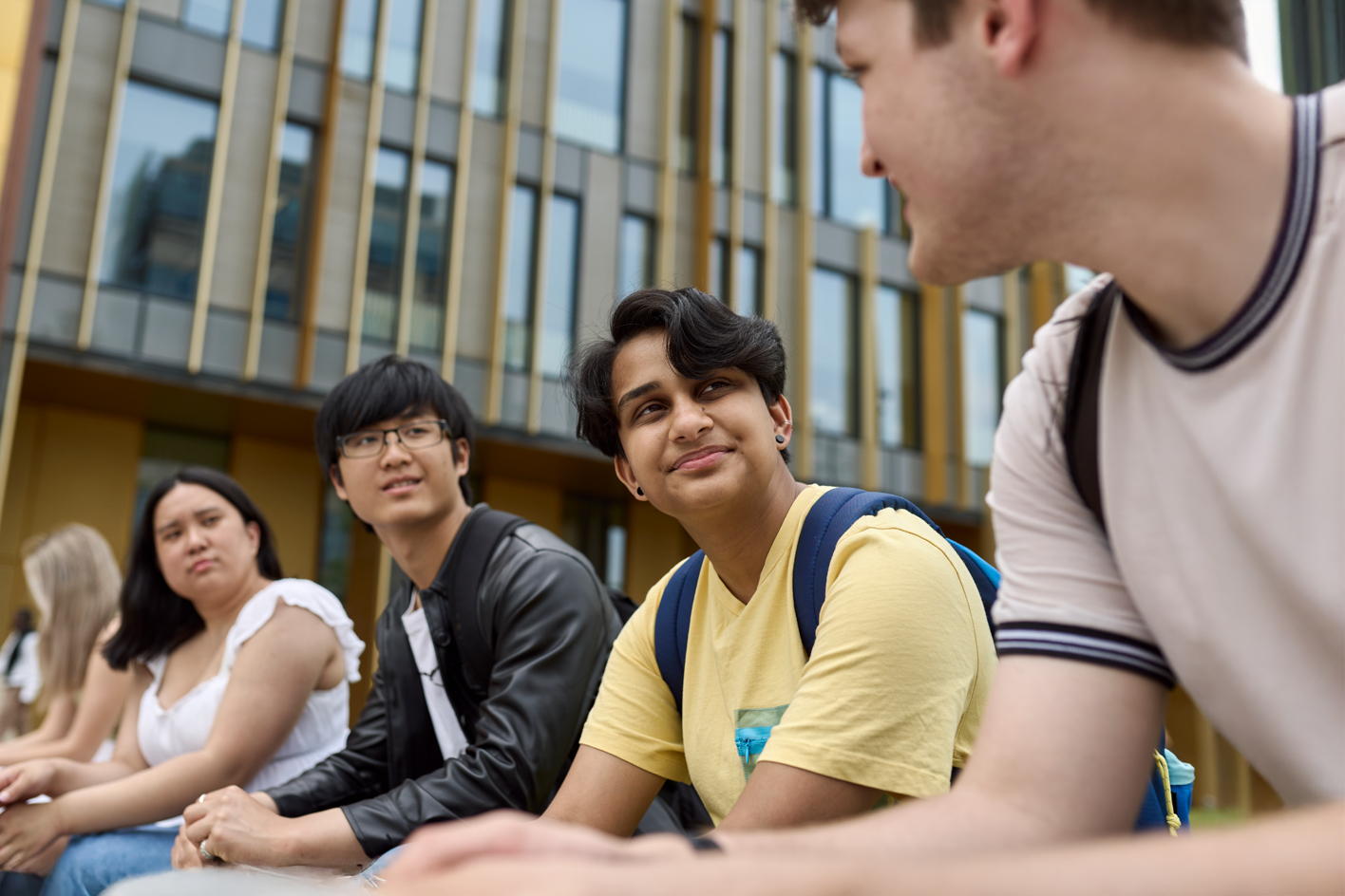 A small group of international students sitting outside the library