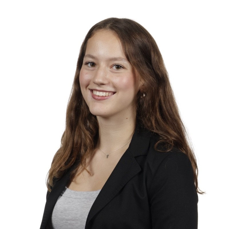 Isoabel wearing a black blazer smiling towards the camera against a white background