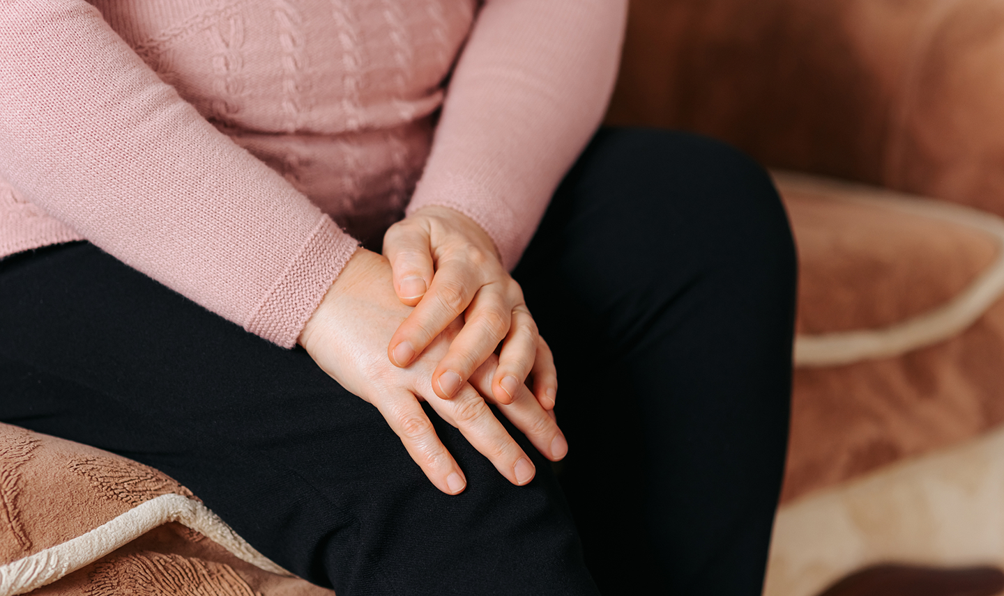 Close-up of older woman holding her knee in pain suffering with sarcopenia.