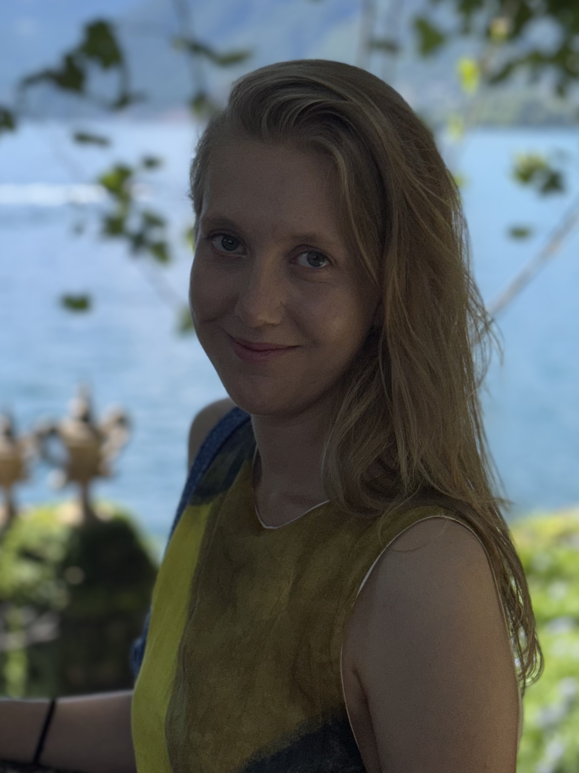 Joana smiles in front of a lake and green space