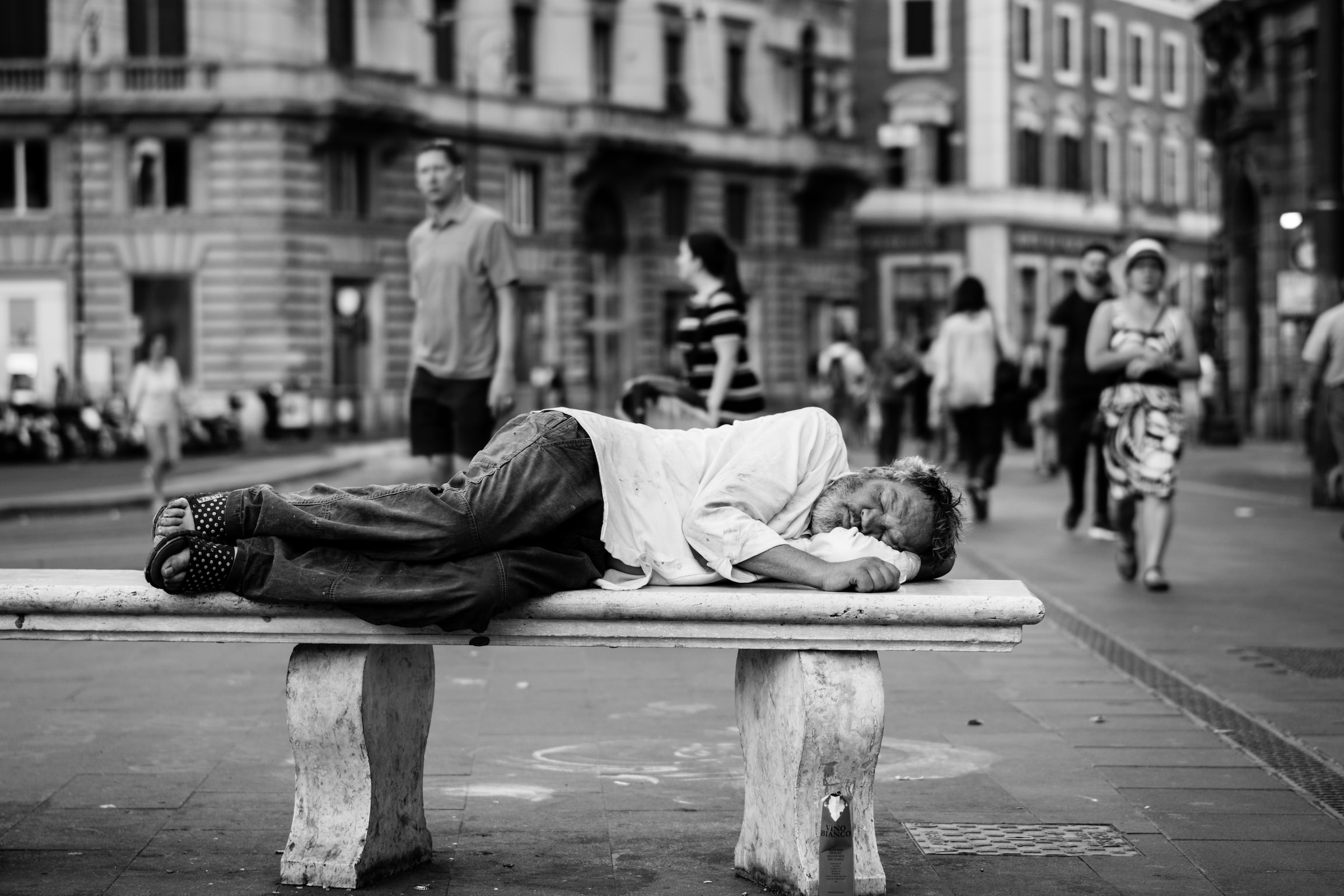 A homeless man sleeping on a stone bench