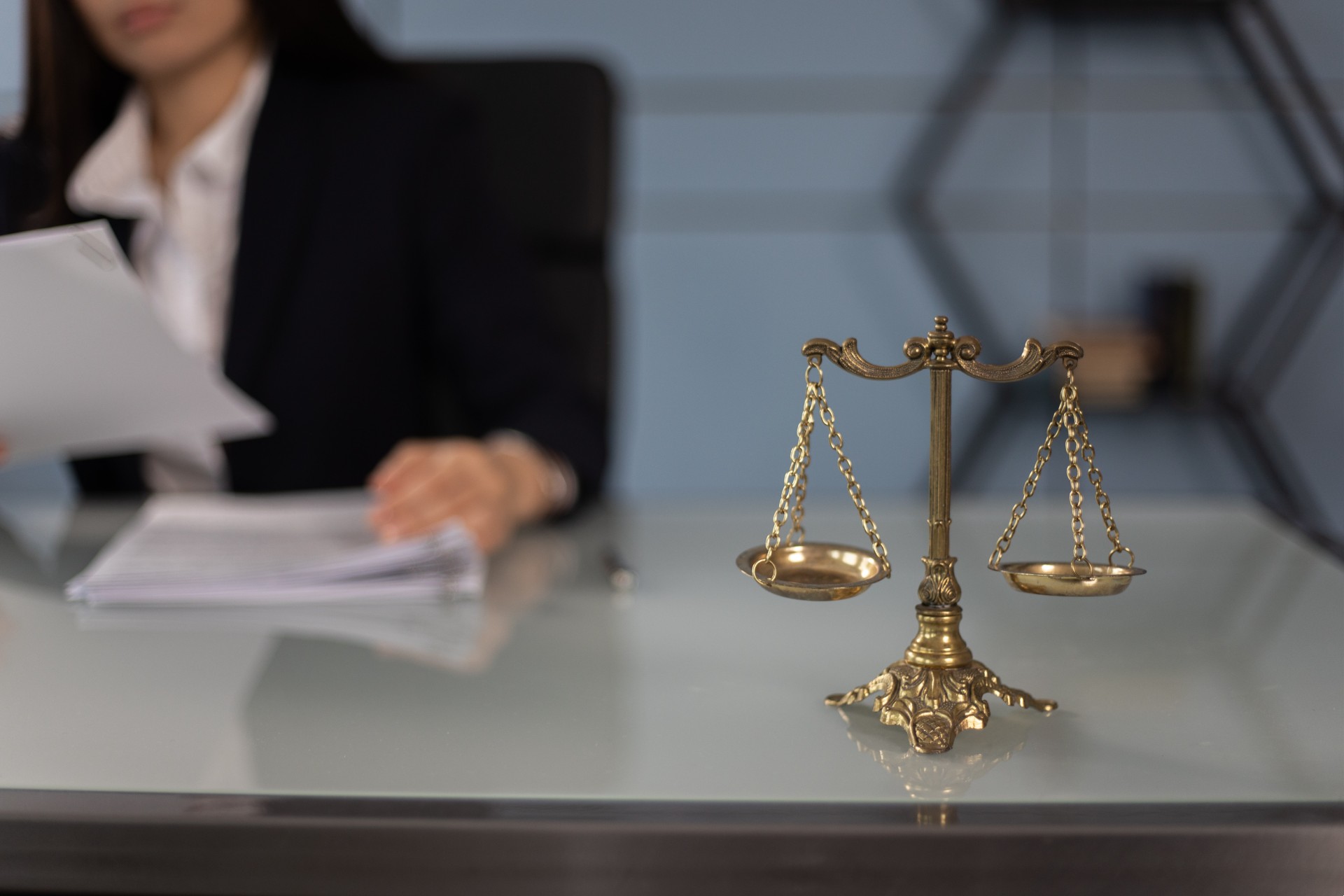 A woman sitting at a desk with scales of justice in the foreground