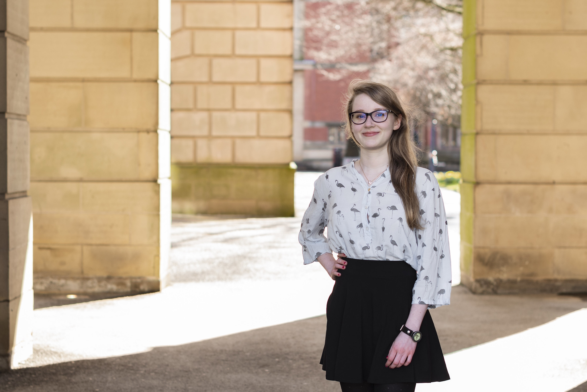 Lina standing in the archways in front of the University of Birmingham's redbrick buildings