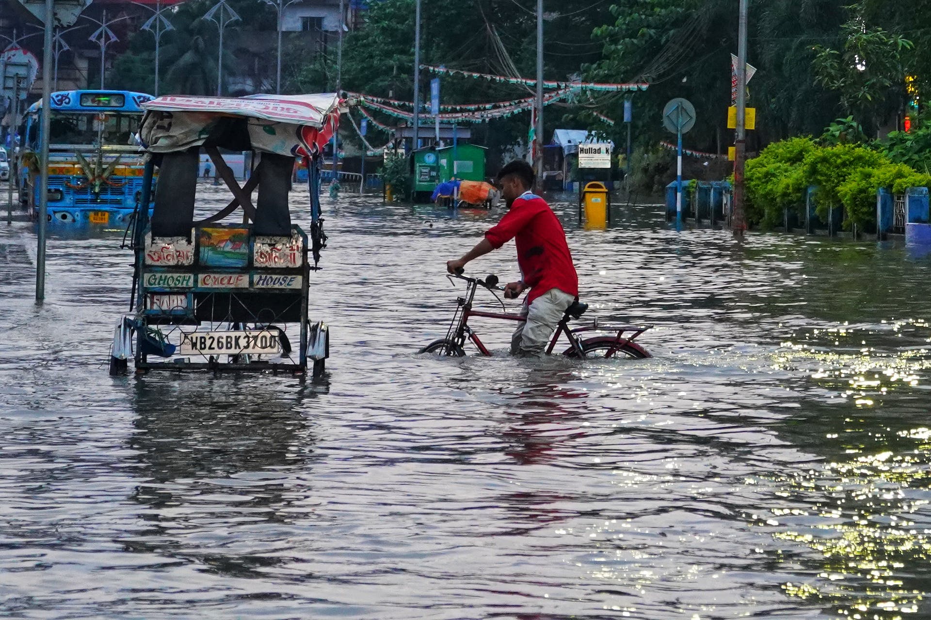 Man on bicycle and empty vehicles in flood water in Kolkata, India