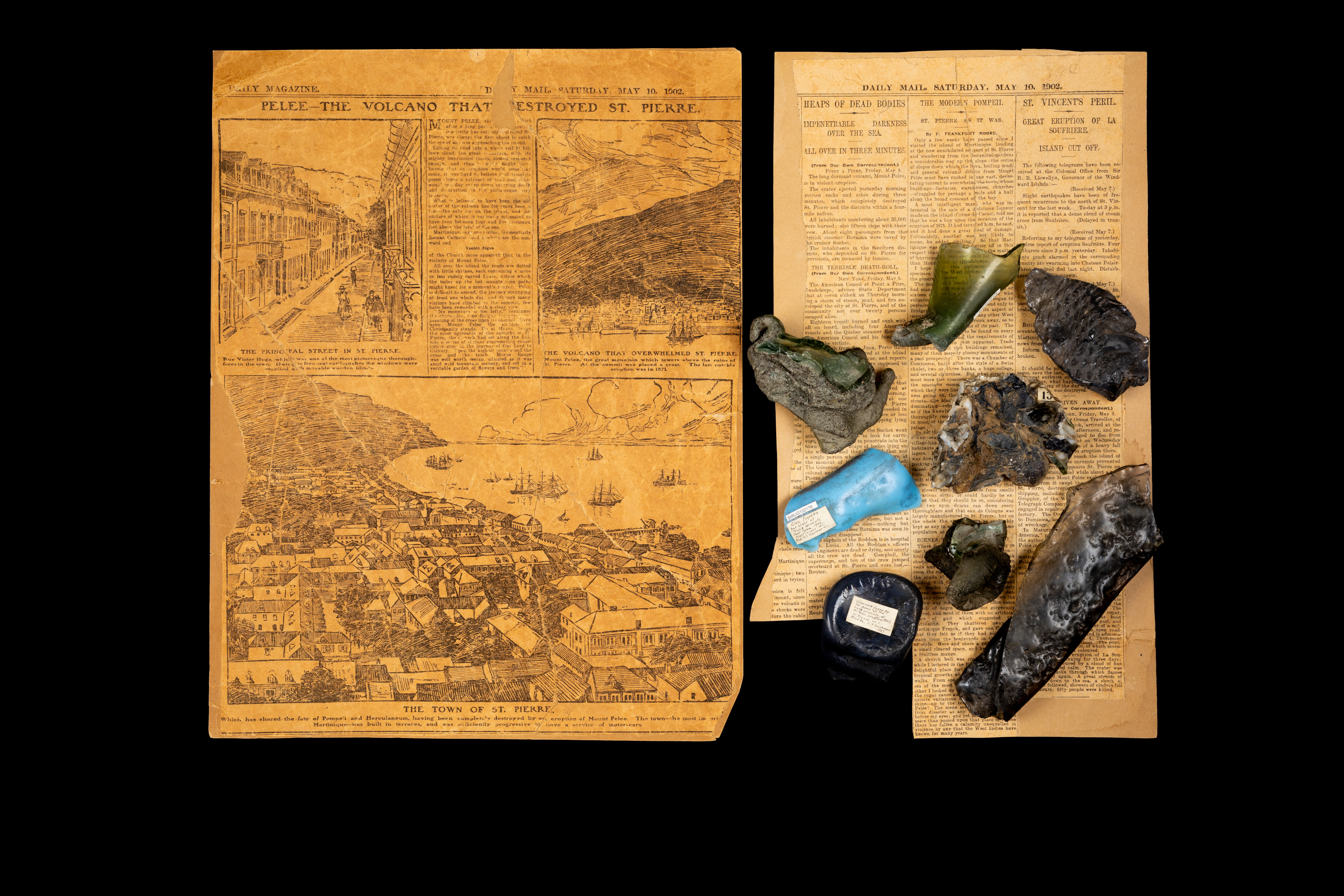 Fragments of lava and warped glass with 20th century newspapers from the Pelée eruption.