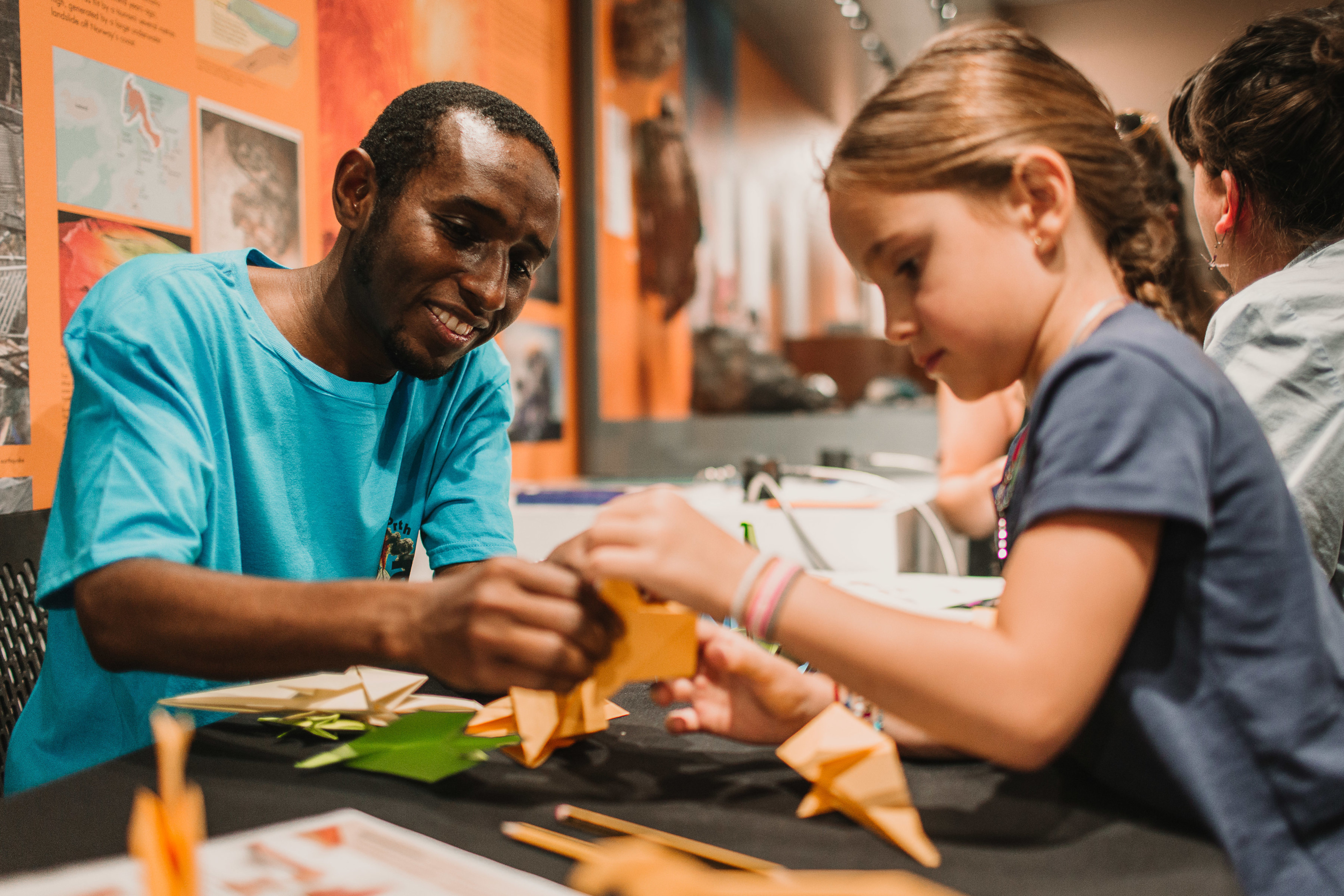 A man helps a girl with a craft.