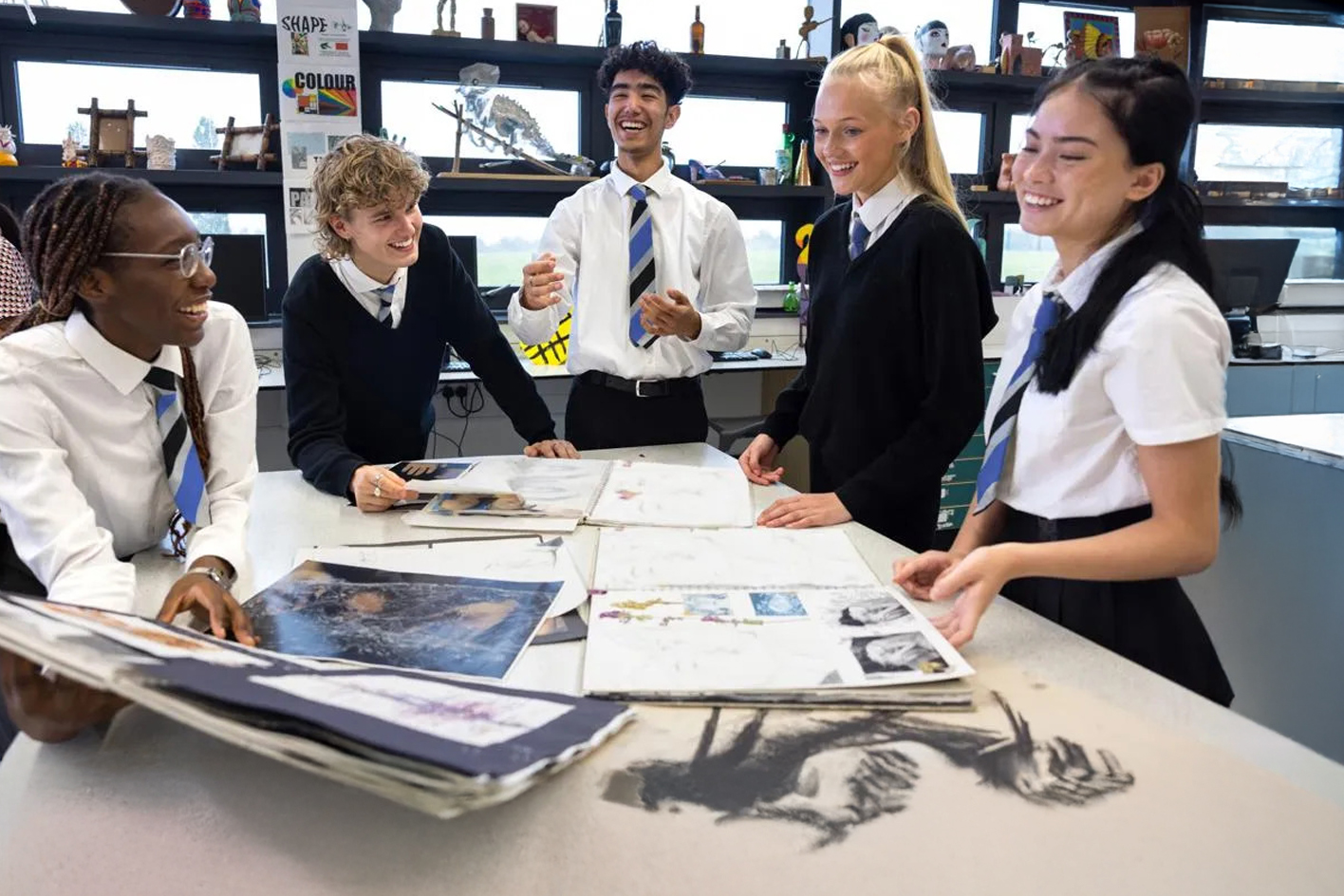 A small group of high school students laughing together in a classroom setting