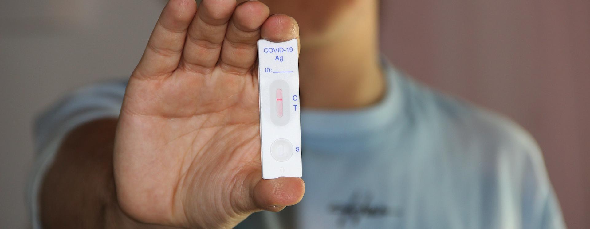 Person holding a lateral flow device test strip showing a negative result