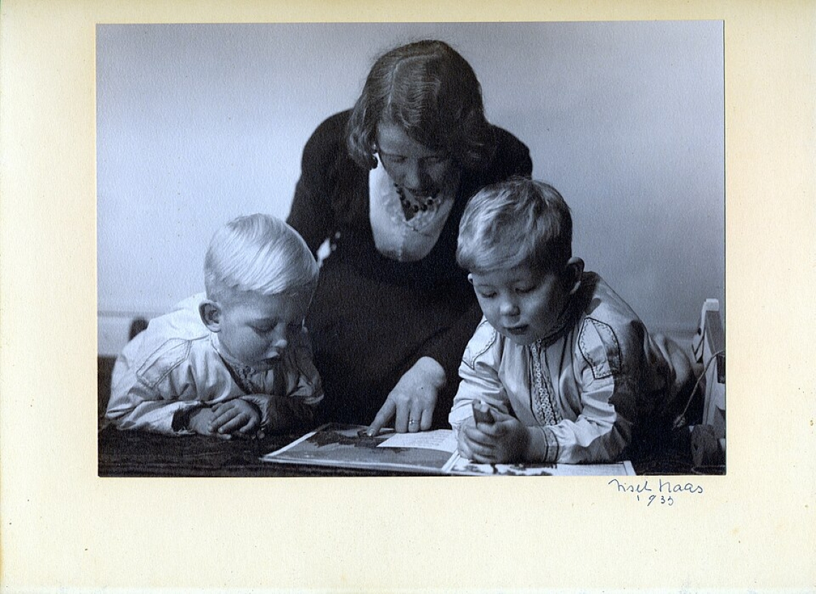 Black-and-white photograph of two children reading with an adult, signed by Lisel Haas.