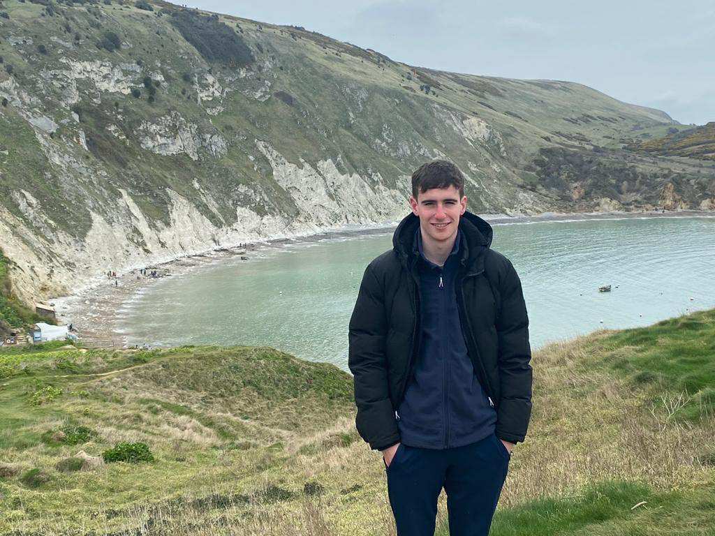Man standing in front of scenic mountains with bright blue lake.
