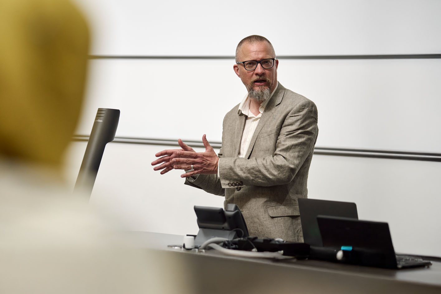Professor Ewan Fernie delivering a lecture with laptops in front of him