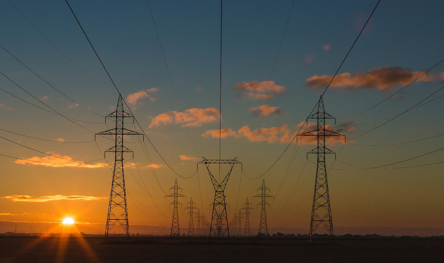 Three electricity pylons at sunset