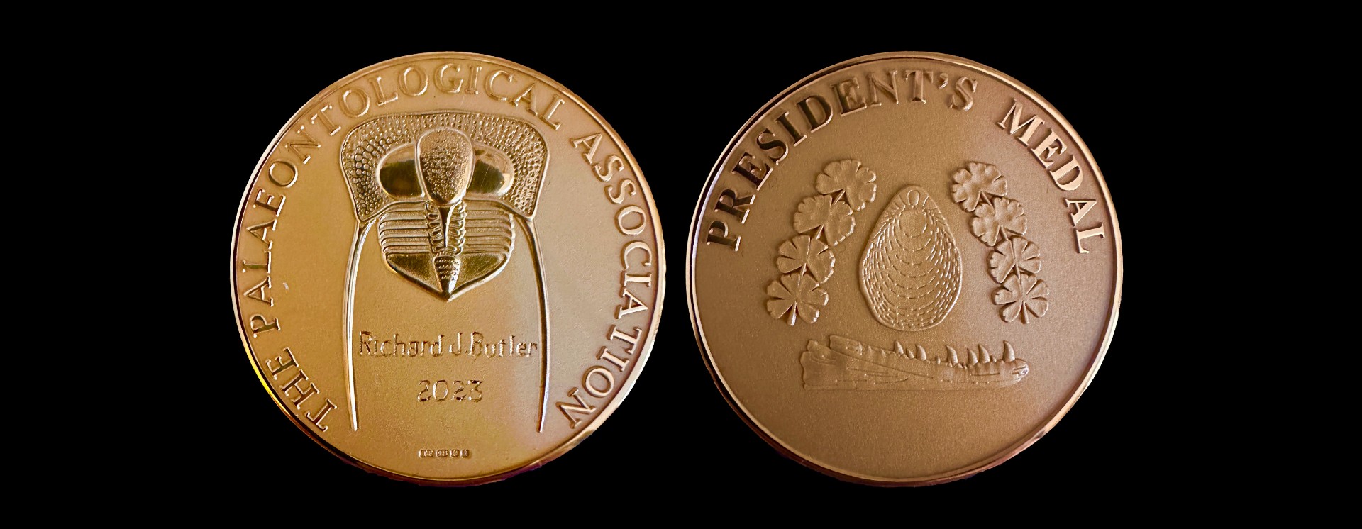 Both sides of a round gold-coloured medal from the Palaeontological Association