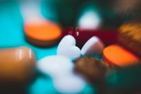 Close up picture of various tablets with one shaped like a heart in focus and others blurry