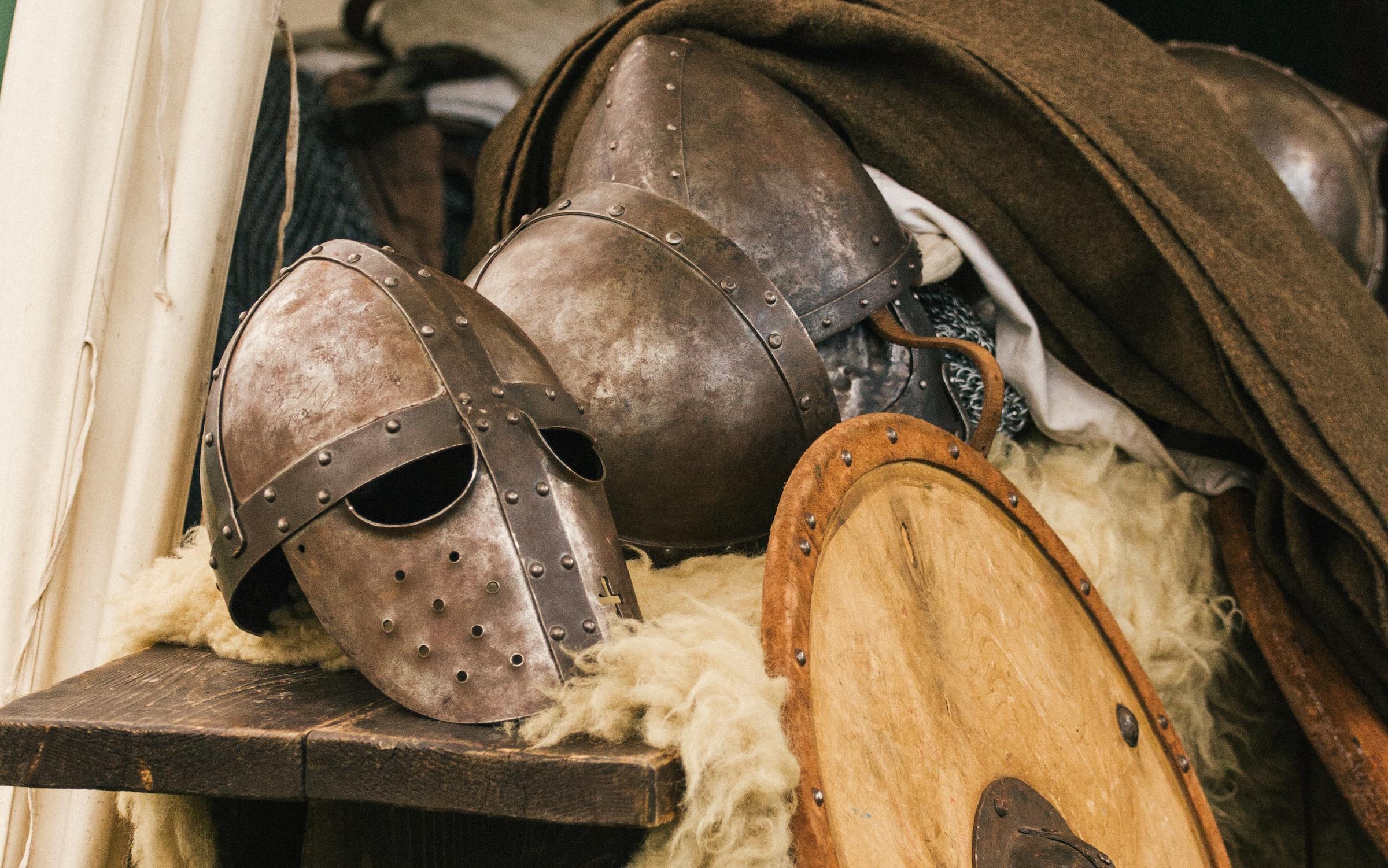 Medieval helmets and shields on an old wooden table