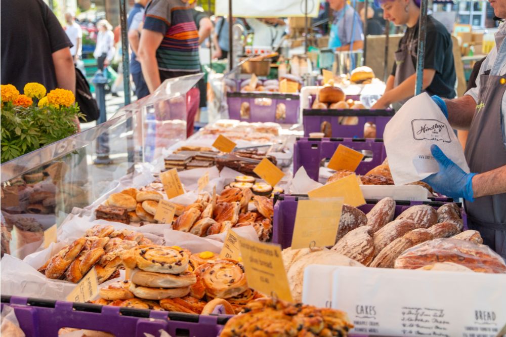 A market stall with baked goods and bright flowers. 